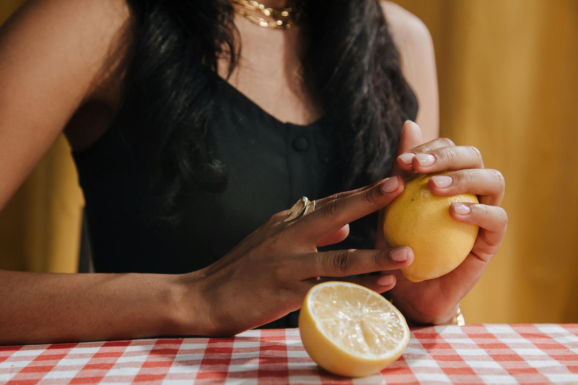 Hand holding a fresh lemon on soft pink background, representing sensory rediscovery after relationship transition