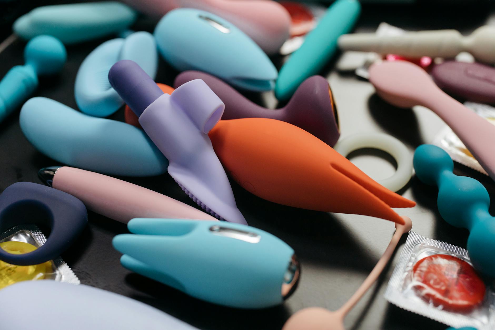 A hand holding a modern vibrator against a minimalist purple backdrop